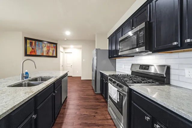 a kitchen with stainless steel appliances granite countertop a sink stove and microwave