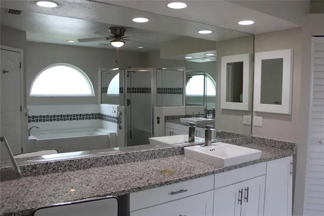 a bathroom with a granite countertop sink a large mirror and a shower