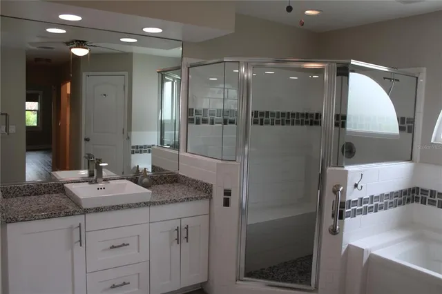 a bathroom with a granite countertop sink a mirror and shower
