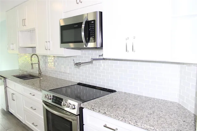 a kitchen with granite countertop a sink and a stove