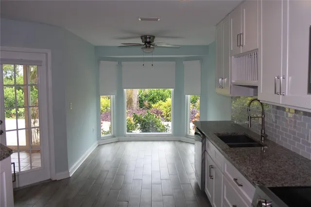 a kitchen with granite countertop a sink window and cabinets