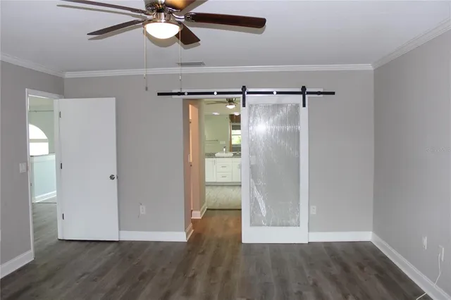 a view of an empty room with wooden floor and a ceiling fan