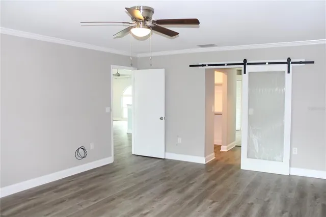 an empty room with wooden floor and ceiling fan