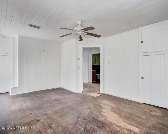 an empty room with windows and fan view