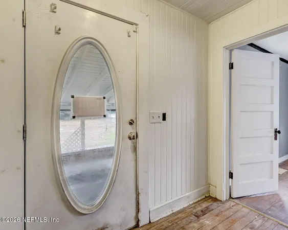 a view of a livingroom with wooden floor and a mirror