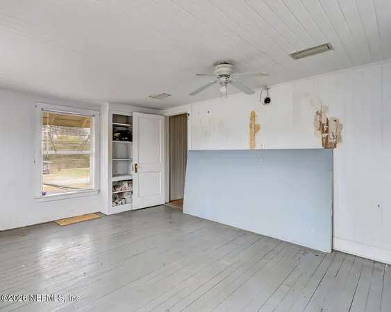 a view of an empty room with a window and wooden floor