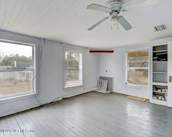 a view of an empty room with a window and wooden floor