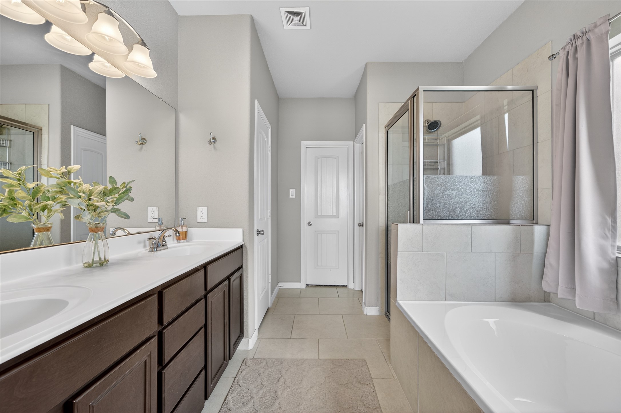 361 Lake Line Drive Alvin, TX 77511 - Photo 12 of 36 Relax in the spa-like primary bathroom, complete with a dual-sink vanity, a deep soaking tub, and a separate glass-enclosed shower with custom tile work.