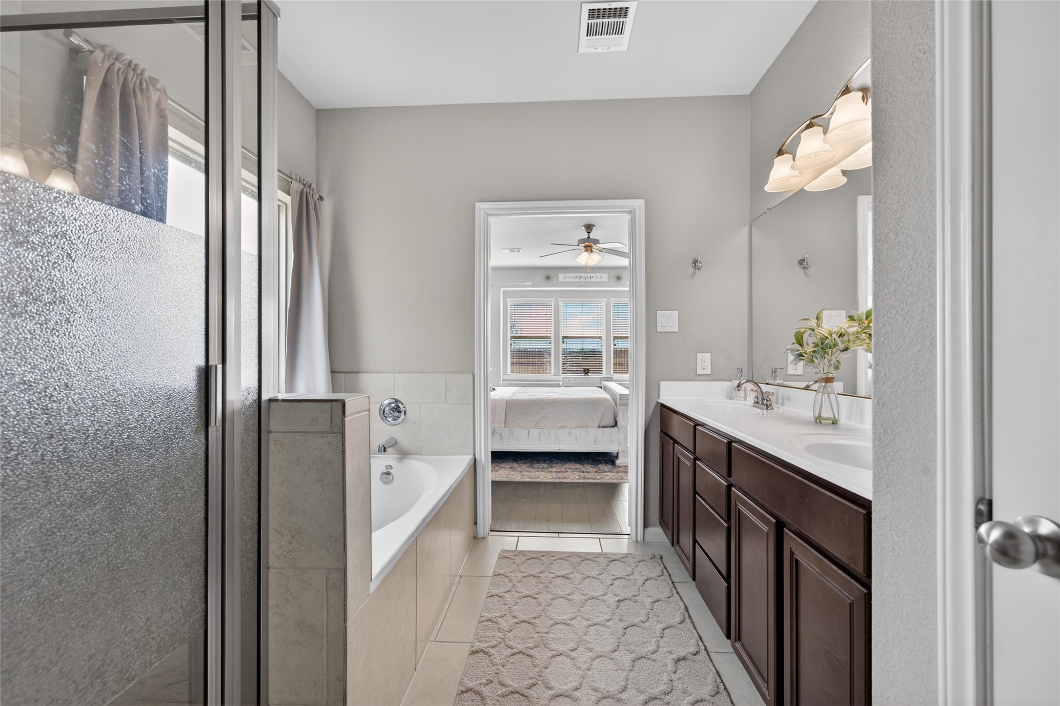 361 Lake Line Drive Alvin, TX 77511 - Photo 13 of 36 Relax in the spa-like primary bathroom, complete with a dual-sink vanity, a deep soaking tub, and a separate glass-enclosed shower with custom tile work.