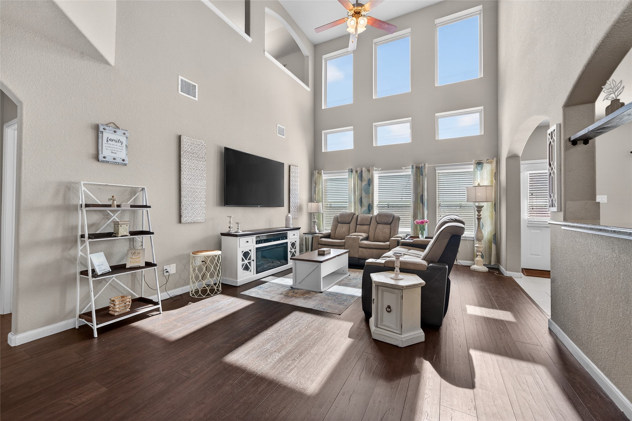 361 Lake Line Drive Alvin, TX 77511 - Photo 36 of 36 Soaring two-story ceilings and a dramatic wall of windows flood the main living area with incredible natural light, creating an airy and grand atmosphere. A versatile floor plan offers plenty of space for a full entertainment center and oversized seating, making this the ultimate spot for movie nights or hosting guests.