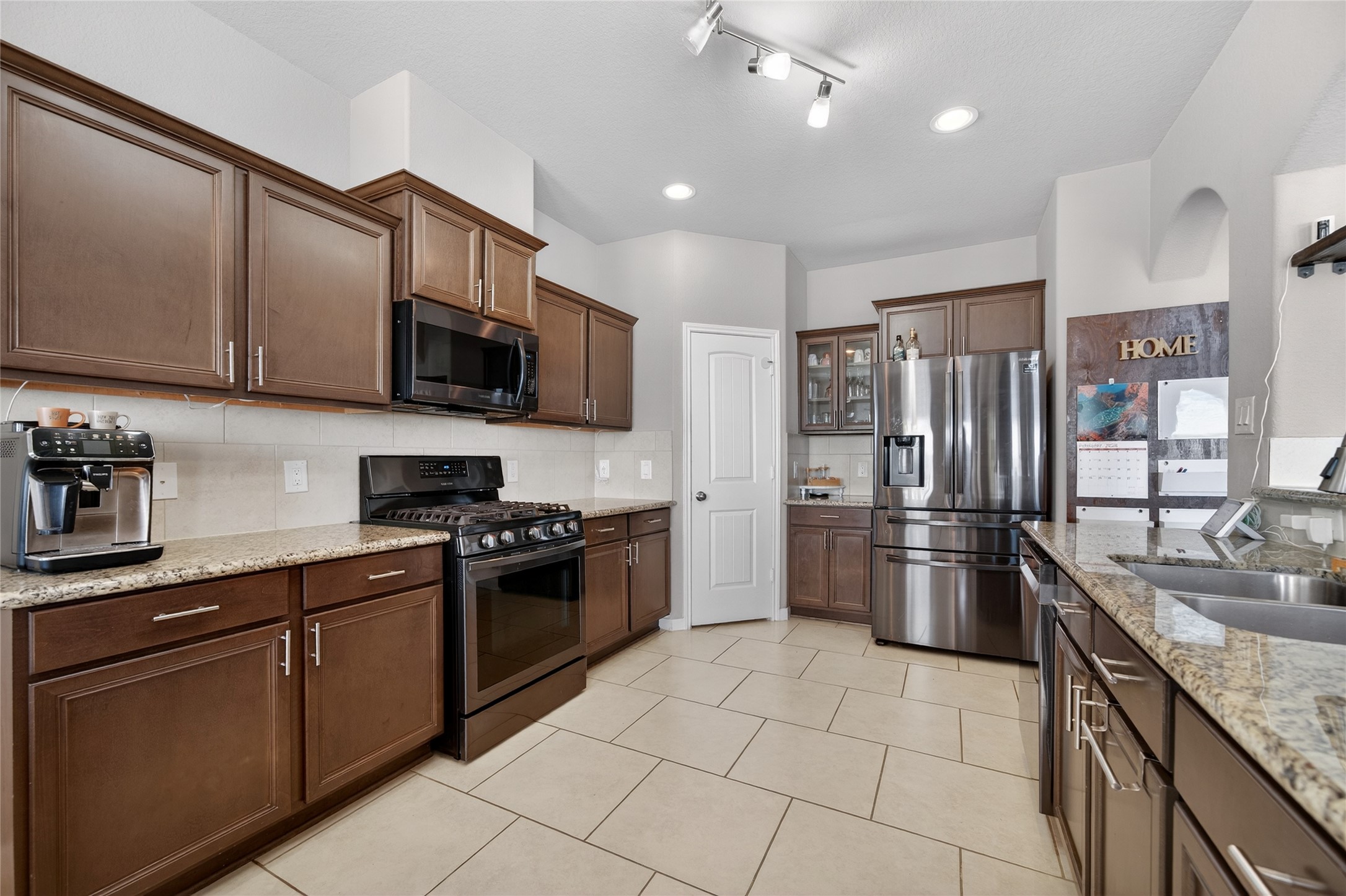 361 Lake Line Drive Alvin, TX 77511 - Photo 5 of 36 The kitchen features rich cabinetry, sleek granite countertops, and stainless steel appliances, all anchored by a large tile floor that flows seamlessly into the dining area.