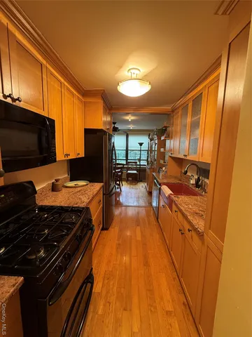 a kitchen with stainless steel appliances a stove top oven a sink a dining table and chairs