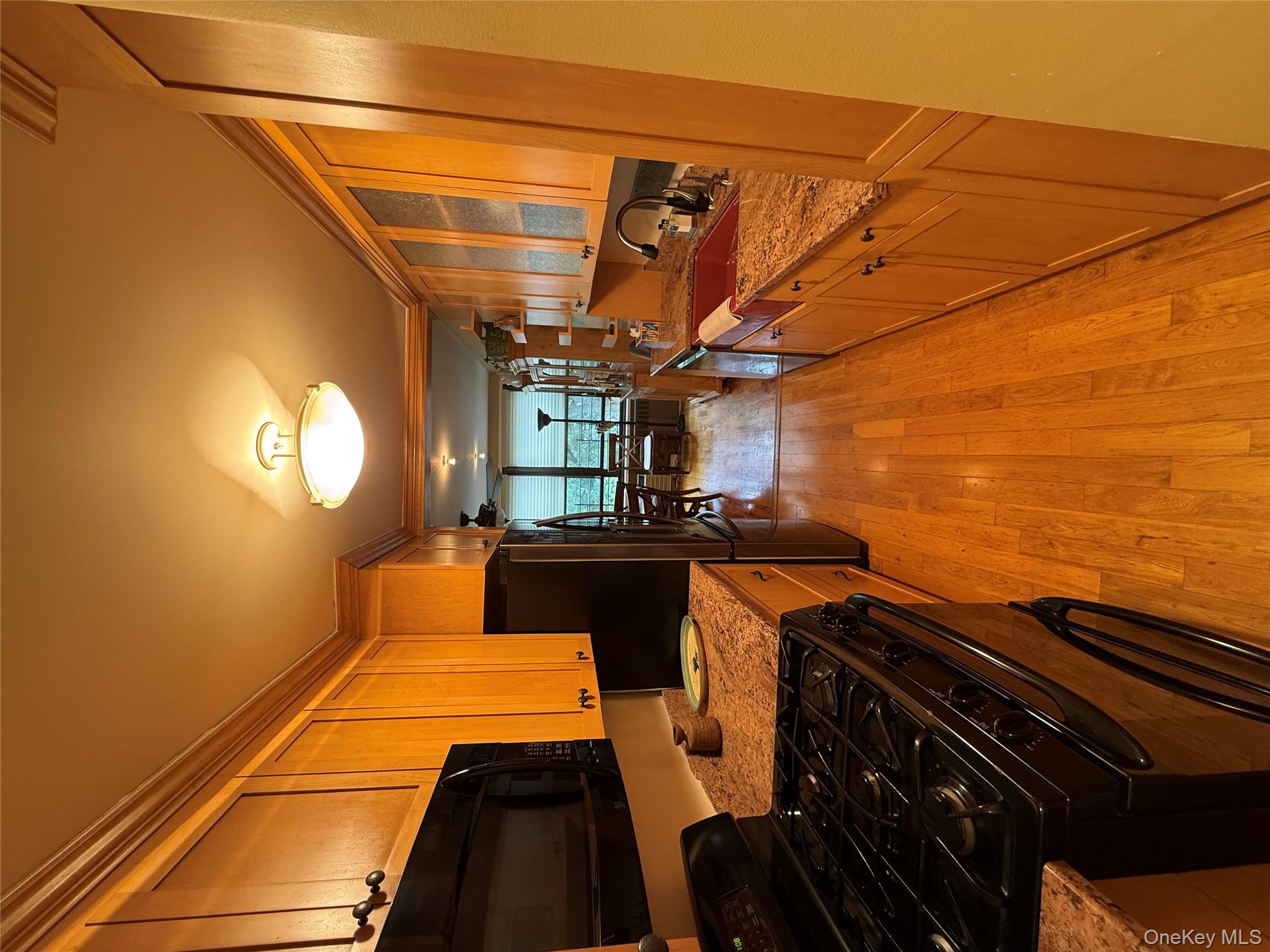 75-34 Bell Boulevard, Unit 6H Queens, NY 11364 - Photo 3 of 8 a kitchen with stainless steel appliances a stove top oven a sink a dining table and chairs