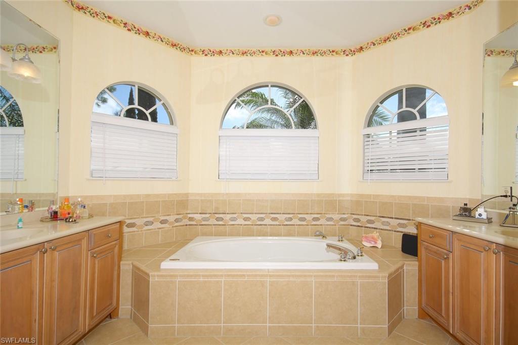 24978 Paradise Road Bonita Springs, FL 34135 - Photo 13 of 25 a bathroom with a tub sink and mirror