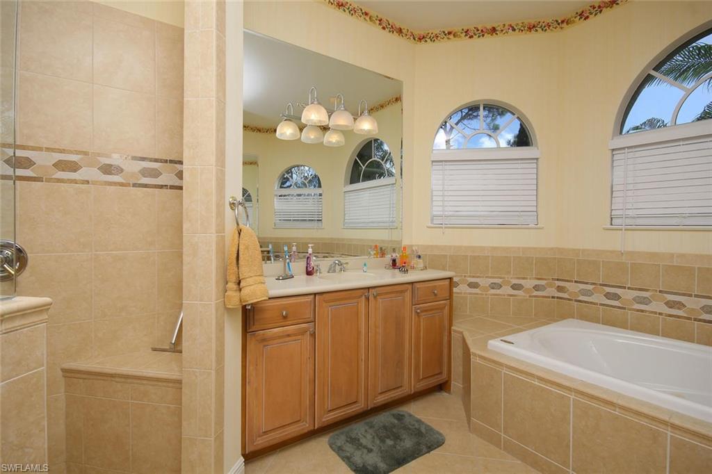 24978 Paradise Road Bonita Springs, FL 34135 - Photo 14 of 25 a bathroom with a tub a sink and a mirror
