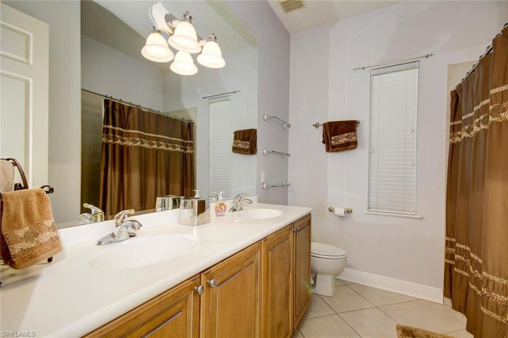 24978 Paradise Road Bonita Springs, FL 34135 - Photo 22 of 25 a bathroom with a sink a toilet and a mirror