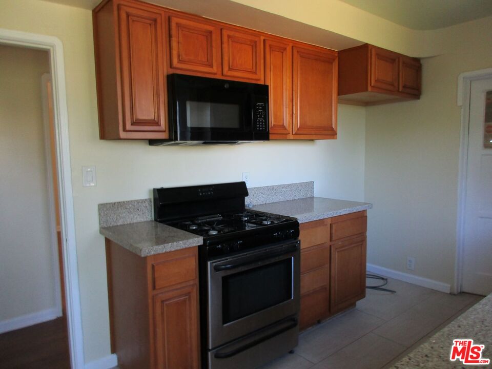 5108 Valley Ridge Avenue View Park, CA 90043 - Photo 17 of 33 a kitchen with stainless steel appliances granite countertop a stove microwave and sink