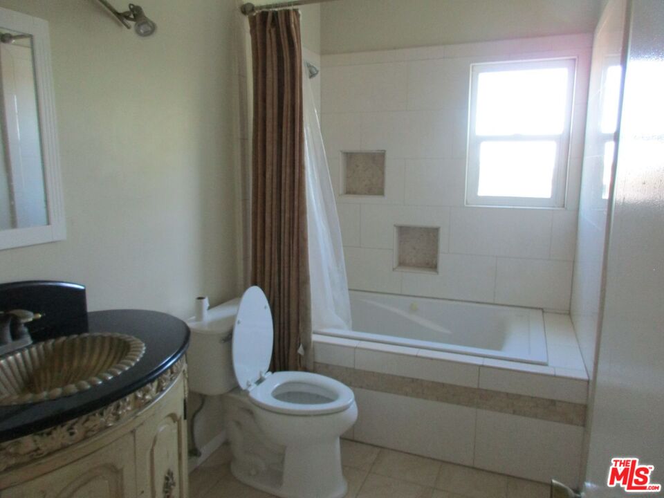5108 Valley Ridge Avenue View Park, CA 90043 - Photo 29 of 33 a bathroom with a granite countertop toilet a sink and bathtub