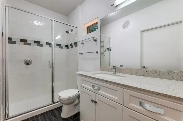 a bathroom with a granite countertop sink a toilet and shower