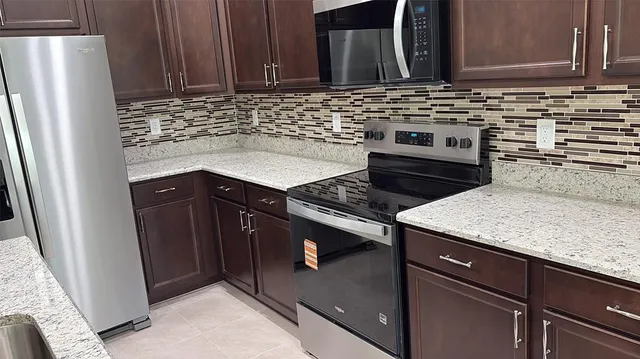a kitchen with granite countertop a sink stove and refrigerator