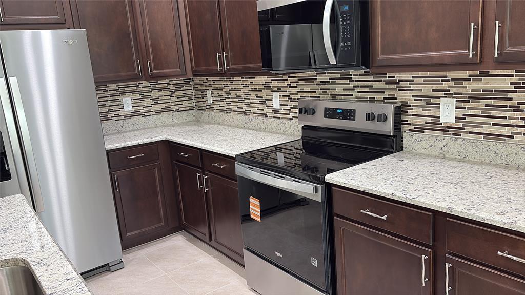 a kitchen with granite countertop a sink stove and refrigerator