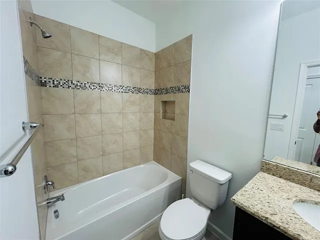a bathroom with a granite countertop bathtub shower sink and toilet