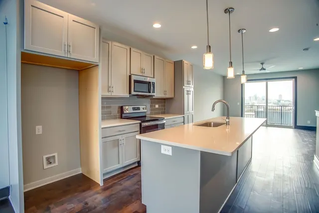 a kitchen with stainless steel appliances granite countertop a refrigerator a sink dishwasher a stove and white cabinets with wooden floor