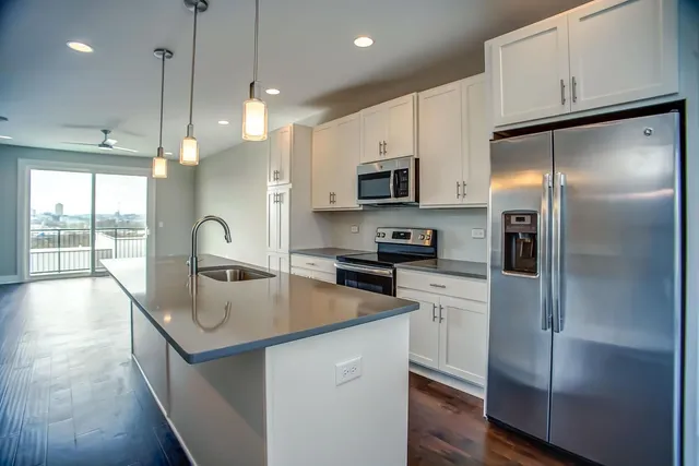 a kitchen with kitchen island a refrigerator stove microwave and sink
