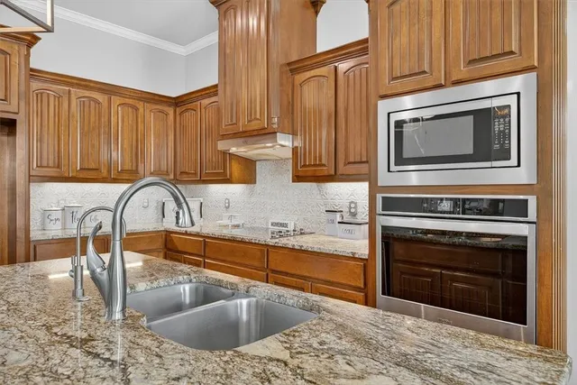 a kitchen with granite countertop a stove a sink and a microwave