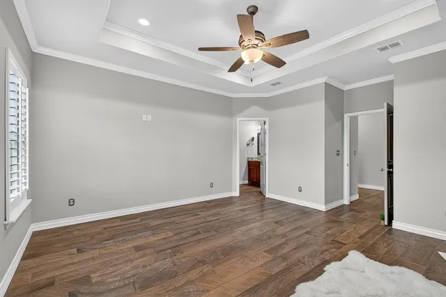 an empty room with wooden floor and ceiling fan