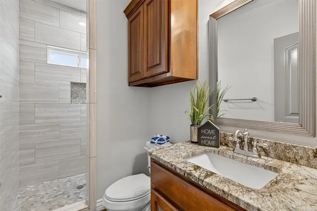 a bathroom with a granite countertop toilet sink and mirror