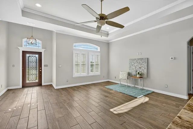 a view of an empty room with a window and wooden floor
