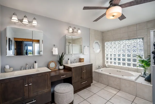 a bathroom with a granite countertop bathtub sink vanity mirror and toilet