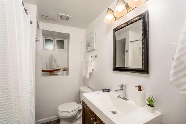 a bathroom with a sink vanity mirror and toilet