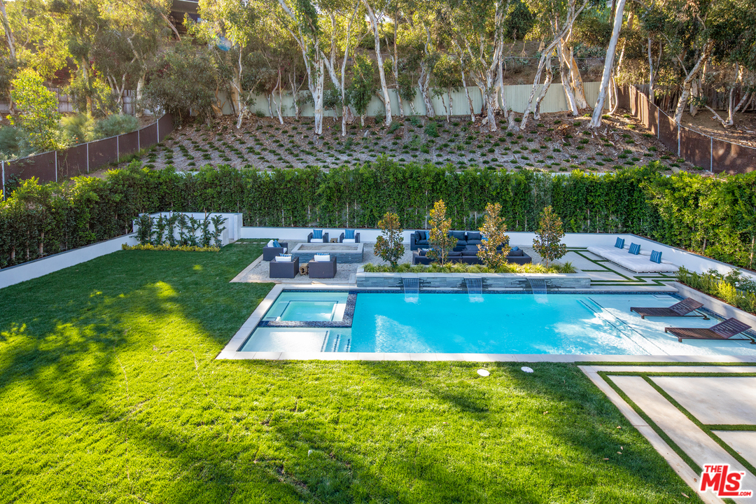 829 Greentree Road Pacific Palisades, CA 90402 - Photo 5 of 50 a view of a swimming pool with a bench and trees in the background