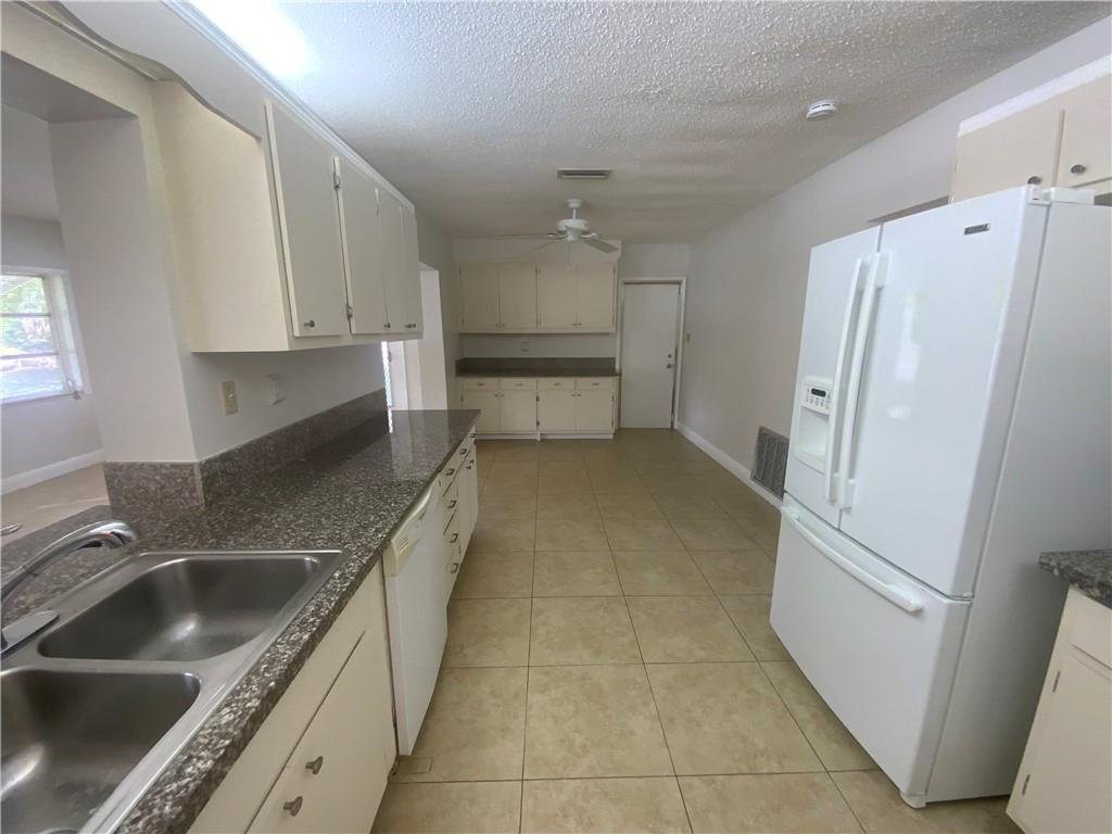 7104 Northwest 70th Street Tamarac, FL 33321 - Photo 16 of 30 a kitchen with a sink a refrigerator and cabinets