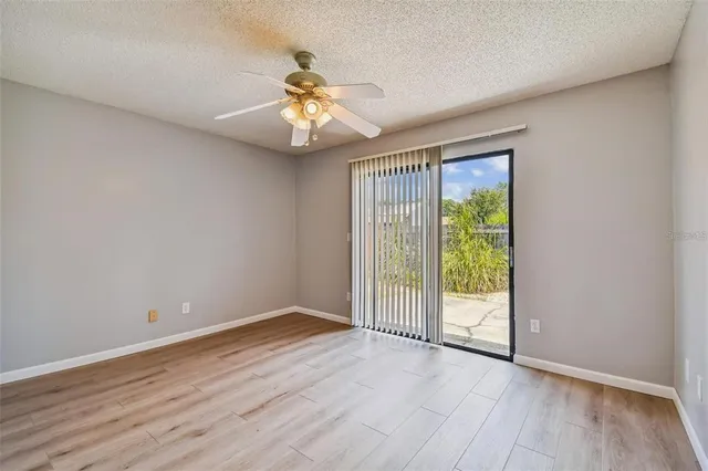 an empty room with wooden floor fan and windows