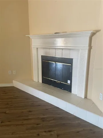 a view of an empty room with wooden floor and a fireplace