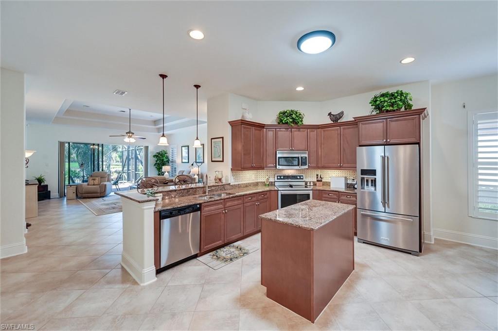 7587 Moorgate Point Way Naples, FL 34113 - Photo 19 of 47 a kitchen with granite countertop stainless steel appliances a refrigerator a stove top oven and sink