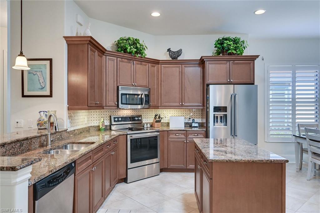 7587 Moorgate Point Way Naples, FL 34113 - Photo 22 of 47 a kitchen with kitchen island granite countertop a sink stainless steel appliances and cabinets