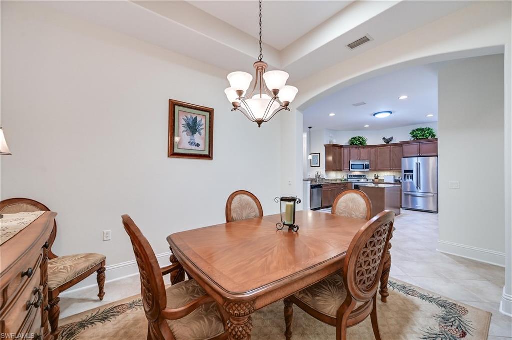 7587 Moorgate Point Way Naples, FL 34113 - Photo 27 of 47 a dining room with furniture and a chandelier