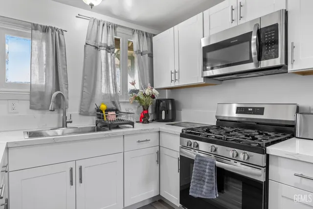 a kitchen with stainless steel appliances white cabinets a sink stove and microwave