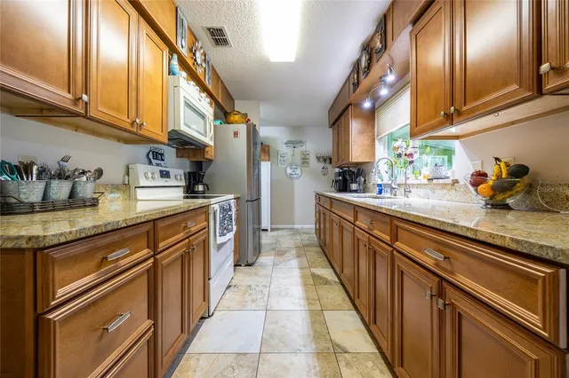 a kitchen with stainless steel appliances granite countertop a sink a stove and cabinets