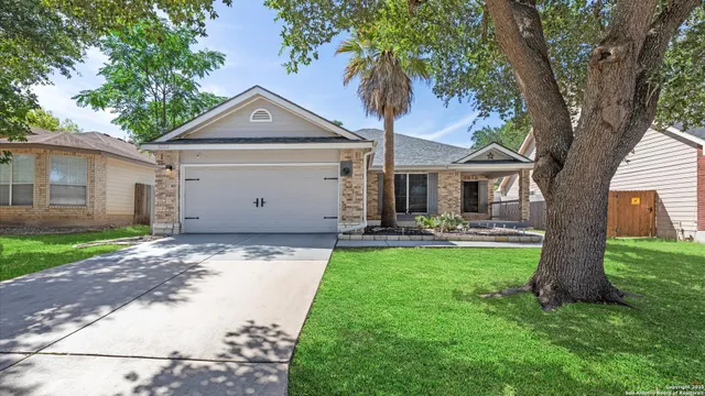 a front view of a house with yard garage and tree