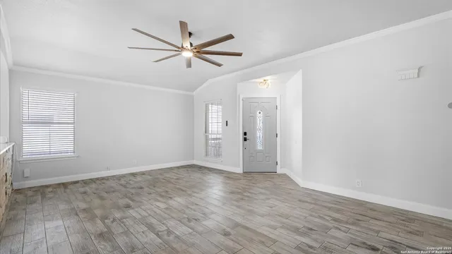 a view of an empty room with wooden floor and a window