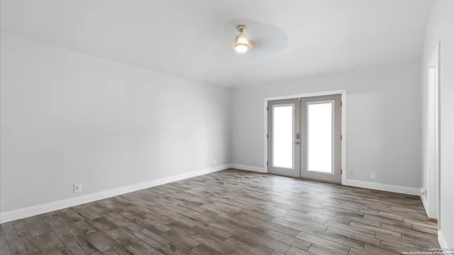 a view of an empty room with wooden floor and a window