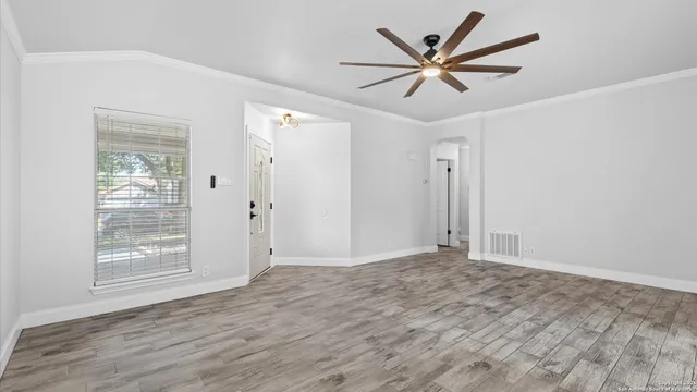 a view of an empty room with cabinet and a ceiling fan