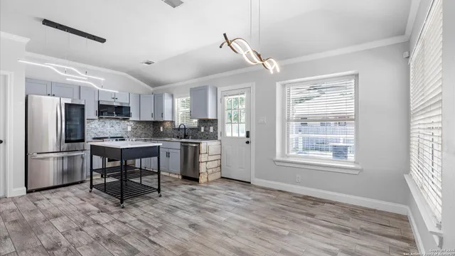 a kitchen with kitchen island a refrigerator and a stove top oven