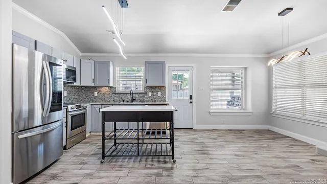 a kitchen with stainless steel appliances granite countertop a refrigerator a sink dishwasher a stove with wooden cabinets and floor