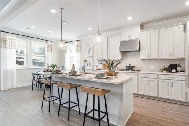 a kitchen with stainless steel appliances a sink a stove a refrigerator cabinets and wooden floor